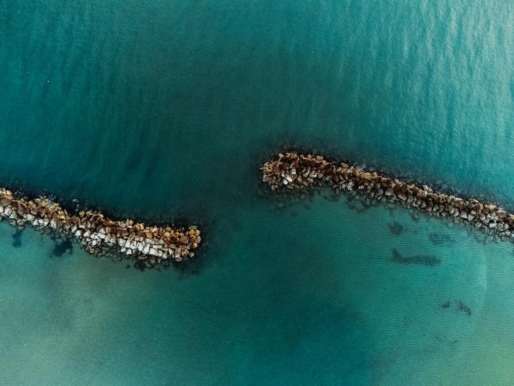 Aerial shot showcasing the beautiful coastal rocks and clear sea of Igea Marina, Italy.